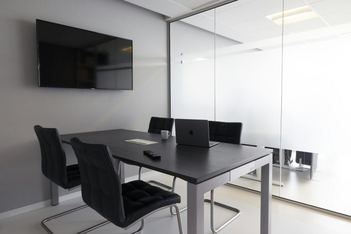 Small empty meeting room with a table, chairs, a television screen and a laptop, ready for a team session