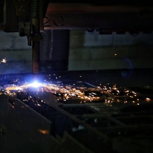 A welder working on a piece of metal, representing industrial surface treatment of metal parts